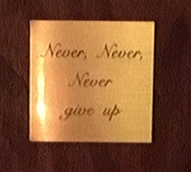 Skylt som det står: "Never, Never, Never give up" på.