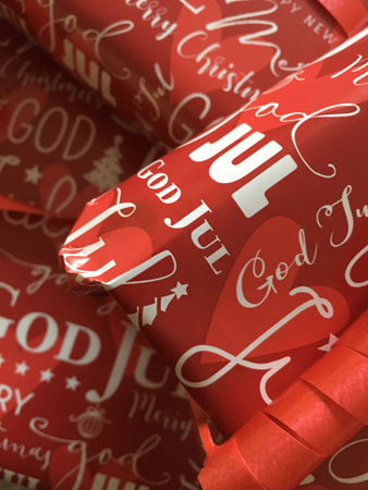 Julklappar rött papper med vit text God jul