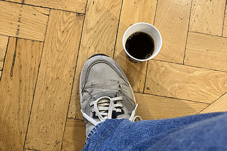 Min fot och kaffemugg på parkett